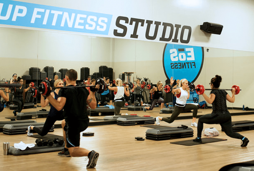 Inside of an EOS fitness class, four people working out with mats and weights
